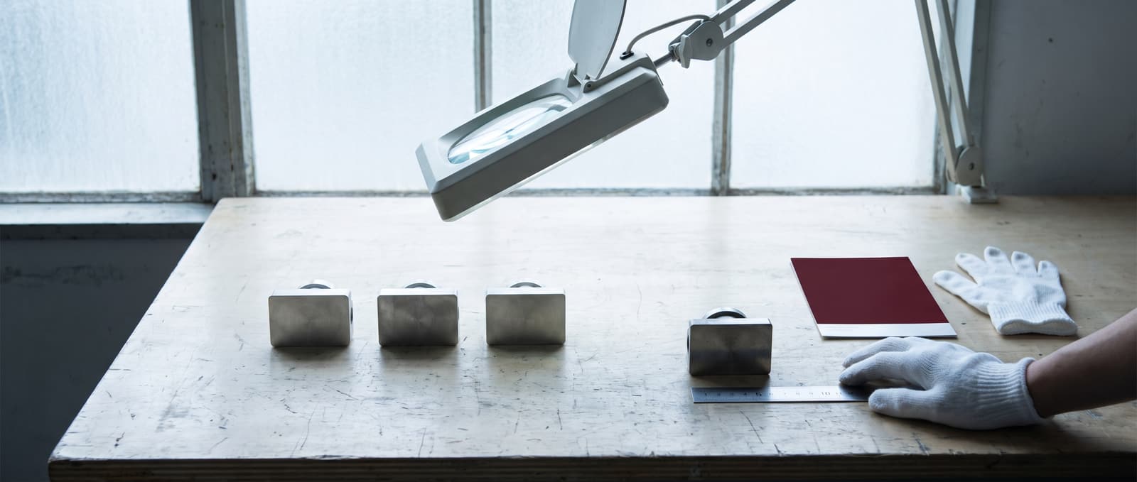 Three product samples under an inspection lamp with one set aside as rejected